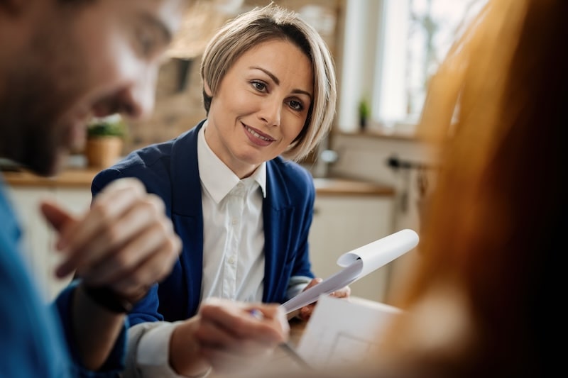 smiling insurance agent going through paperwork communicating with her clients during meeting min